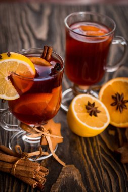 Sıcak baharatlı baharatlar ile mulled şarap ve turuncu. Limon, tarçın ve koyu ahşap arka plan üzerinde kakule.