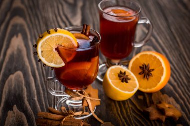 Sıcak baharatlı baharatlar ile mulled şarap ve turuncu. Limon, tarçın ve koyu ahşap arka plan üzerinde kakule.