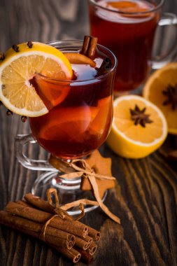 Sıcak baharatlı baharatlar ile mulled şarap ve turuncu. Limon, tarçın ve koyu ahşap arka plan üzerinde kakule.