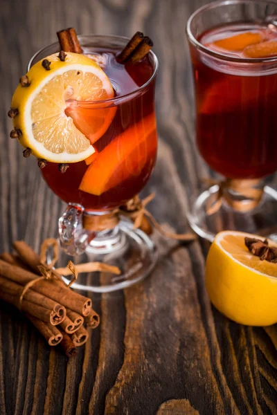 Warme glühwein met pittige kruiden en oranje. Citroen, kaneel en kardemom op een donkere houten achtergrond. — Stockfoto