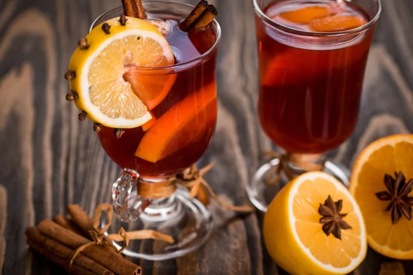 Vinho quente com especiarias picantes e laranja. Limão, canela e cardamomo sobre um fundo de madeira escura . — Fotografia de Stock