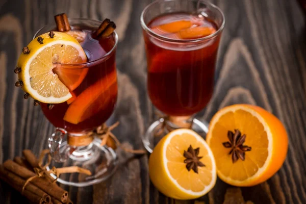 Warme glühwein met pittige kruiden en oranje. Citroen, kaneel en kardemom op een donkere houten achtergrond. — Stockfoto