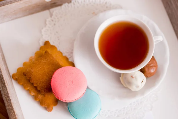 Weiße Tasse heißen Tee, Makkaroni und frische Shortbread-Kekse mit Schokoladenbonbons. Geschmack: Minze und Erdbeere. auf einer Serviette. Glückwunsch zum Valentinstag — Stockfoto