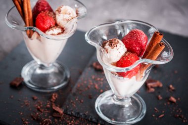 Bir cam bardak, çilek mus, tarçın ve çikolata koyu gri arka plan üzerinde taze çilek vanilyalı dondurma