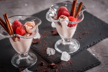 Bir cam bardak, çilek mus, tarçın ve çikolata koyu gri arka plan üzerinde taze çilek vanilyalı dondurma