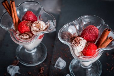 Bir cam bardak, çilek mus, tarçın ve çikolata koyu gri arka plan üzerinde taze çilek vanilyalı dondurma