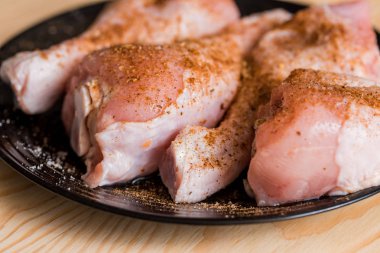 Tibia tavuk, tavuk budu siyah bir kaplama, ahşap arka plan, baharatlar ve tuz hazırlanması