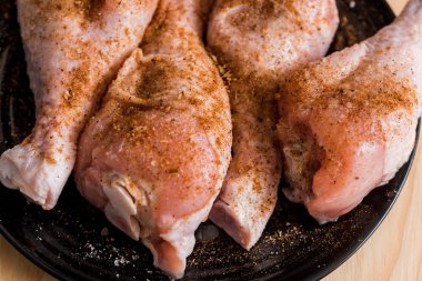 Tibia tavuk, tavuk budu siyah bir kaplama, ahşap arka plan, baharatlar ve tuz hazırlanması