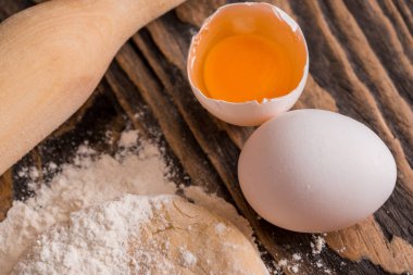 Ekmek pişirme işlemi. Pasta, ekmek, rulo ve bisküvi pişirme için hamur hazırlama. Ahşap koyu arka plan üzerinde yumurta ile un. Hamur için oklava yanındaki.