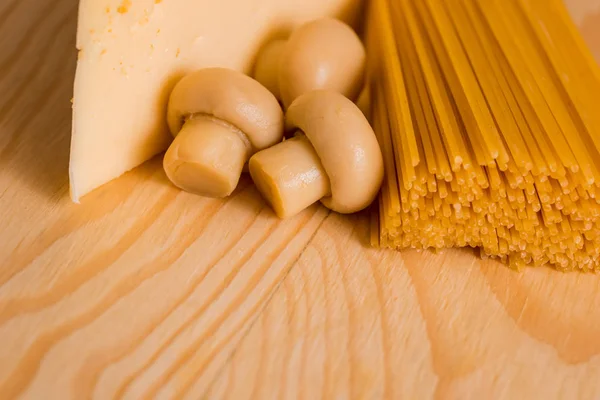 Zubereitung von Spaghetti mit Käsepilzen. Eier und Sauerrahmsoße, Champignons auf einem Schneidebrett auf Holzgrund — Stockfoto