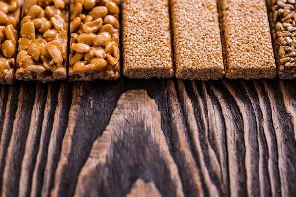 Nuts in caramel, honey ,sugar glaze nuts, seeds, flax seeds on a dark wooden texture background. Snack food. Unhealthy eating. Copy space, top view