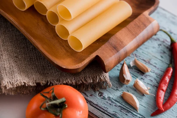 Pastas de canelones sin cocer sobre tabla de cortar e ingredientes. Cocina italiana — Foto de Stock