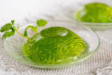 Yeşil jöle ile beyaz bir arka plan üzerinde keten peçeteye cam nane yaprakları.