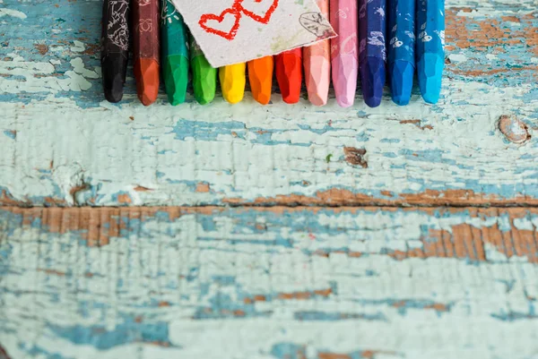 Multicolored pencils like a rainbow on Valentine's Day on a wooden table. Two red hearts on paper. Copy space, top view — Stock Photo, Image