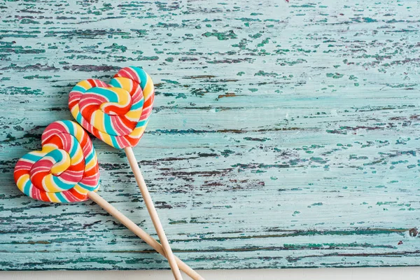 Lollipops arco-íris colorido doce listrado como coração no fundo azul. Conceito engraçado . — Fotografia de Stock