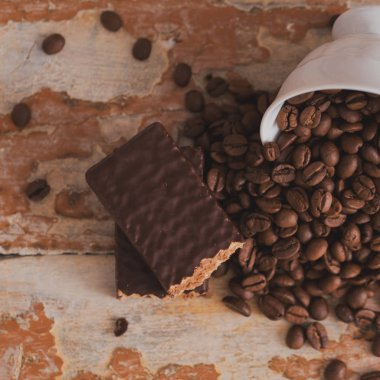 Kahve taneleri ile ahşap bir arka plan üzerinde dağınık. Çikolatalı gözleme, tatlı tatlı