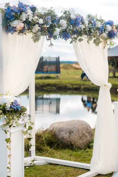 O arco de casamento é decorado com flores azuis e seda clara branca. Cerimônia de casamento de verão — Fotografia de Stock
