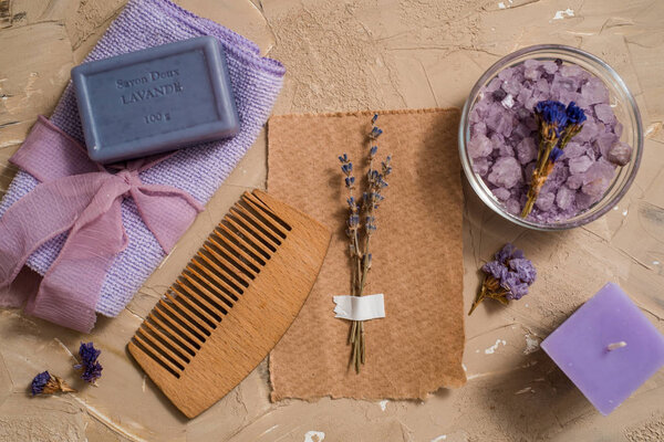 Purple sea salt, a wooden comb towel on a concrete brown background.
