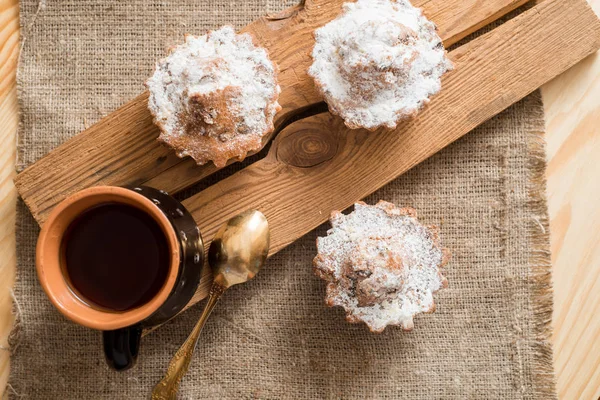 Sammansättningen av choklad och vanilj cupcakes med socker pulver för te gången. Hemlagade bakverk koncept. Stjärnigt formad metall kex form och muffins liggande på rutigt tyg. Te cookies på trä bakgrund — Stockfoto