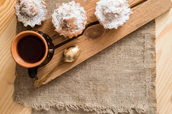 Composição de cupcakes de chocolate e baunilha com açúcar em pó para a hora do chá. Conceito de pastelaria caseira. Forma de biscoito de metal em forma de estrela e muffins deitados em pano xadrez. Biscoitos de chá no fundo de madeira — Fotografia de Stock