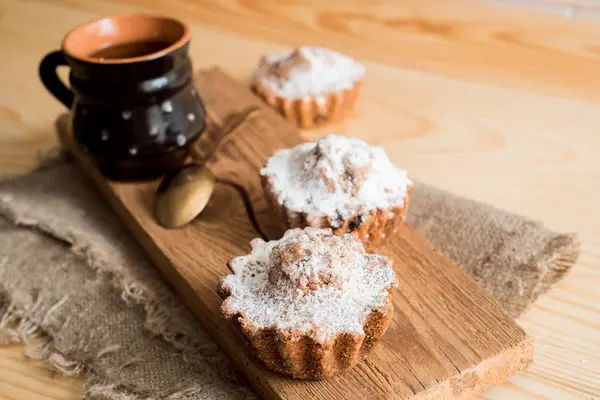 Compositie van chocolade en vanille cupcakes met suiker poeder voor theetijd. Zelfgemaakte gebak concept. Ster vormig metalen biscuit vorm en muffins liggend op geruite doek. Thee cookies op houten achtergrond — Stockfoto