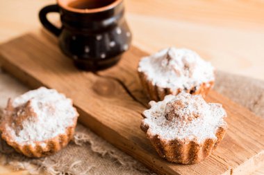 Bir kil fincan sıcak çay ve kuru üzüm ile bahar kompozisyon çikolatalı kek. Kek üzerine pudra şekeri. Sabah tatlı kahvaltı ahşap bir masa üzerinde