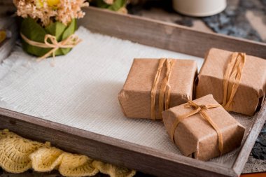 Üç ahşap bir masa üzerinde gri bir beton zemin üzerine kraft sunulu liste kutularında hediye. Senin yazıt için bir yer