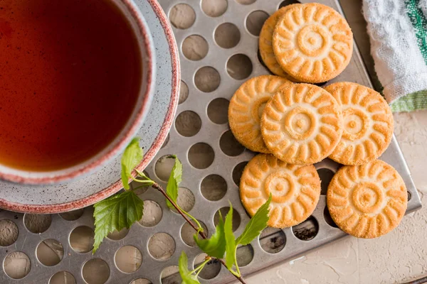 Зелений чай в чашці. Чашка чаю з круглим печивом на зеленій лляній картатій серветці і вінтажний залізний лоток, зелене листя на гілці берези, весняні бутони. Ранковий сніданок . — стокове фото