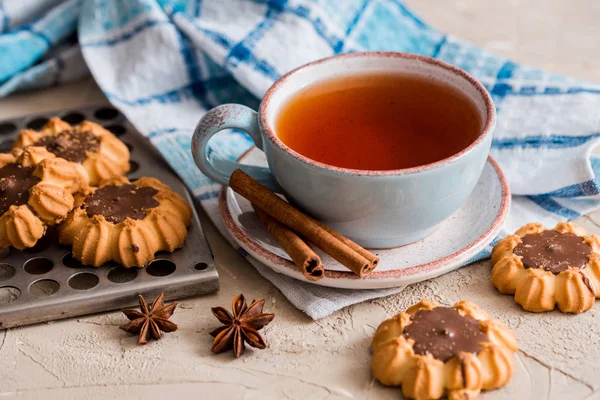 Tea in a blue clay vintage cup with chocolate-flavored biscuits on a metal tray. Blue linen napkin on a table on a concrete background — Stock Photo, Image