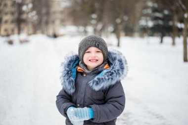 Having oyunculuk ile kar, açık havada kar yağışı sırasında renkli kış giysileri sevimli küçük komik çocuk. Etkin açık havada eğlence kışın çocuklu. Çocuk ile sıcak şapka, eldiven el ve eşarp