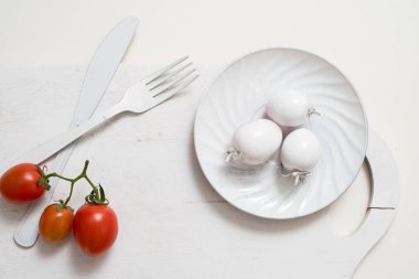 Domates stok görüntüleri grup. Beyaz çatal bıçak plaka üzerinde eski bir ahşap tahta tepsi. Sanat fikir beyaz domates, boya ile boyanmış. Parlak nokta üç kırmızı domates. Taze kırmızı domates