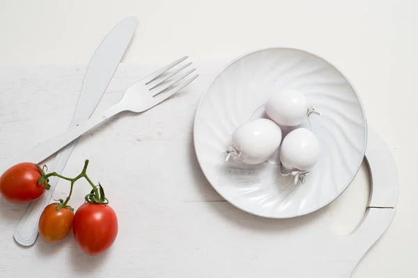 Manojo de imágenes de stock de tomates. Placa de cuchillo de tenedor blanco en una antigua bandeja de madera. Idea de arte tomates blancos, pintados con pintura. Mancha brillante tres tomates rojos. Tomates rojos frescos — Foto de Stock