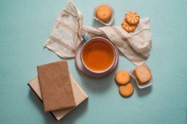 bir uçan daire, çeşitli çerezleri, eski küçük kitap bir mavi arka plan üstten görünüm üzerinde bir kil mavi bardak çay