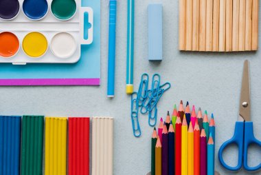 derslerde iyi hazırlık. Okul aksesuarları renk hamuru, çok renkli kalemler, ataş makas kalem ve suluboya boya. Üstten Görünüm