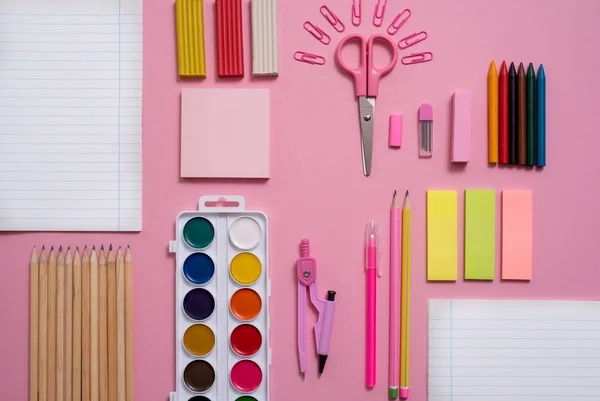 Sobre un fondo rosa, accesorios escolares y un bolígrafo, lápices de colores, un par de brújulas, un par de brújulas, un par de tijeras. Copiar espacio, vista superior —  Fotos de Stock