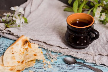 Çay eski bir kupa, ince pasta pasta sonraki, kiraz çiçekleri bir mavi ahşap arka plan yakın çekim, wabi sabi serisi