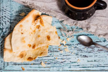 Bir fincan çay bir kil eski kupa, keten peçeteye bir ahşap mavi arka plan, waby sabi tarzında bir kuru düz kek rusk