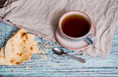 Bir fincan çay bir kil eski kupa, keten peçeteye bir ahşap mavi arka plan, waby sabi tarzında bir kuru düz kek rusk