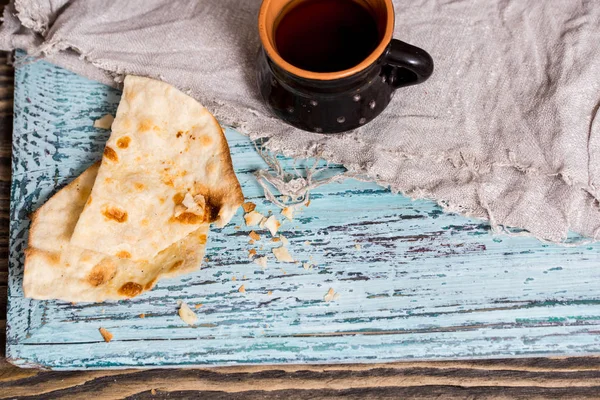 Bir fincan çay bir kil eski kupa, keten peçeteye bir ahşap mavi arka plan, waby sabi tarzında bir kuru düz kek rusk