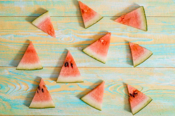 Slices of watermelon on old blue and yellow wooden background. Chopped watermelon. summer, harvest and vacation concept. Flat lay, top view. — Stock Photo, Image