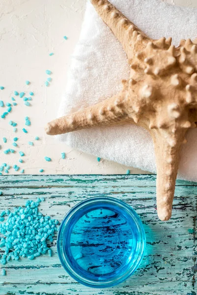 Hermosa composición de spa azul. sal marina azul, jabón líquido, estrellas de mar, conchas y una toalla de baño blanca — Foto de Stock