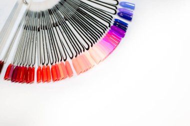 Manikür dolabı, güzellik salonunda bir kız için jöle ojesi. Beyaz arka planda kozmetik mağazasında palette farklı oje renkleri var, gökkuşağı gibi. Boşluğu kopyala.