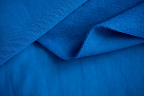 Katlanmış parlak mavi saten kumaş parçası beyaz arka planda izole edilmiş, üst manzara. Pamuk kumaş kıvrımları. Sıcak palto. Mavi rengin güzel dokusu. Terzi kesimi için bir parça kumaş.. — Stok fotoğraf
