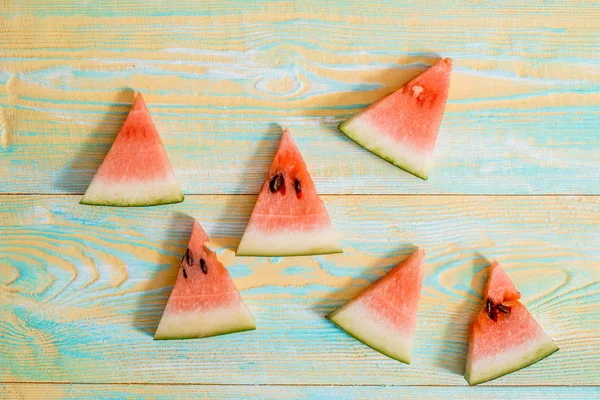 Skivor av vattenmelon på gamla blå och gula trä bakgrund. Hackad vattenmelon. sommar, skörd och semester koncept. Platt ligg, ovanifrån. — Stockfoto