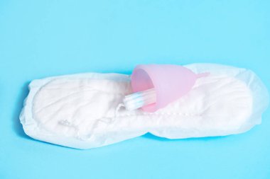 Mavi arka plan üzerine kurulmuş kadınsı mahrem hijyen. Hijyenik ped, pamuklu çubuk veya bardak. Modern bir kadının seçimi.