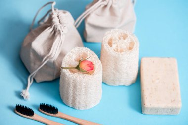 Sıfır atık ev, mavi arka planda kozmetik ekolojik ürün. Bambu fırçası, sebze lifleri, pamuk havlu. Düz konum kopyalama alanı.