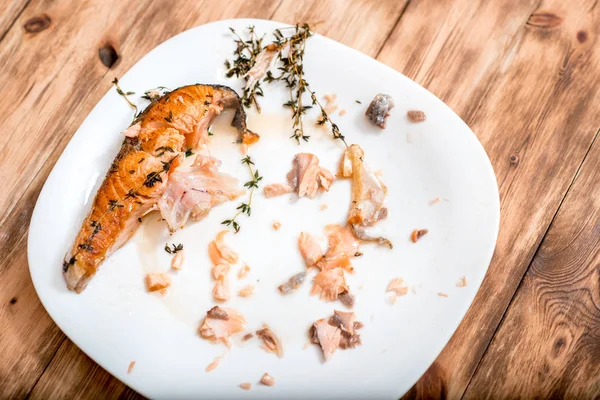 Стейк из жареной лосося, крупным планом. грязная посуда, кусок красной рыбы и кость на тарелке. вкусные объедки . — стоковое фото
