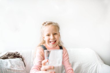 Kız kahvaltıda kefir ya da süt içer. Komik bıyık. Evdeki kanepede gülüyordu. sağlıklı beslenen çocuklar