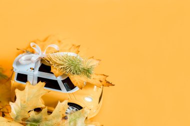 Oyuncak araba yırtık kağıtları delip geçer, sonbaharda sarı kağıt üzerinde. Sıcak ve modern sonbahar konsepti. Eğilim sarı arka plan. Düz konum, üst görünüm, kopyalama alanı.