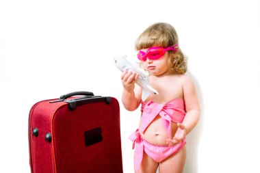 Pembe bavul, pembe mayo giyen kız, yüzmek için gözlük. Neşeli, tatlı ve çok güzel bir manken. Utangaç bir ifadeyle duran sevimli küçük kız, izole edilmiş beyaz. Yaz tatili kavramı